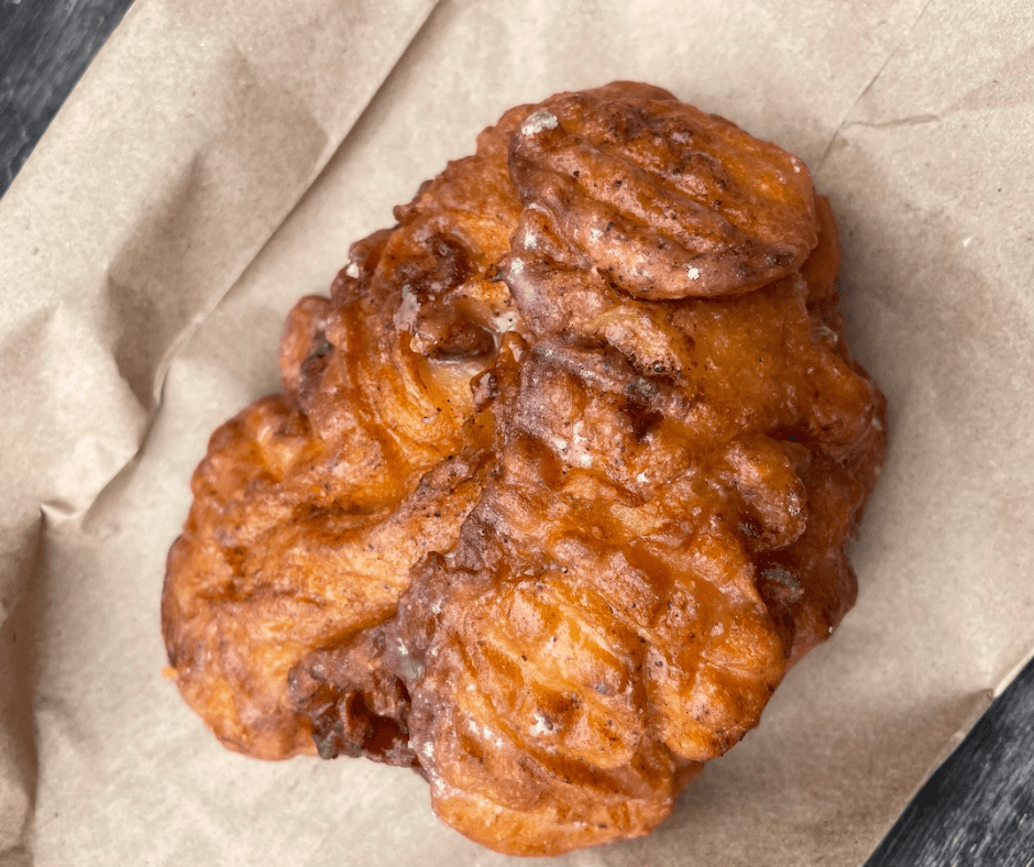 apple fritter sitting on a brown paper bag