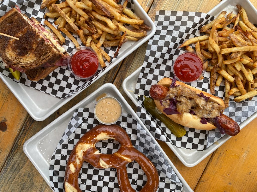 A giant spread of fries, a reuben sandwich, a bratwurst and a giant pretzel at Trestle Brewing Company