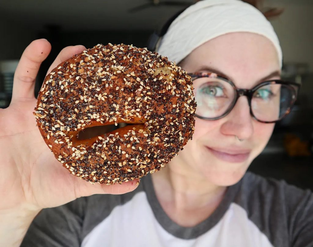 Lauren of Red Hen holding a bagel up to the camera