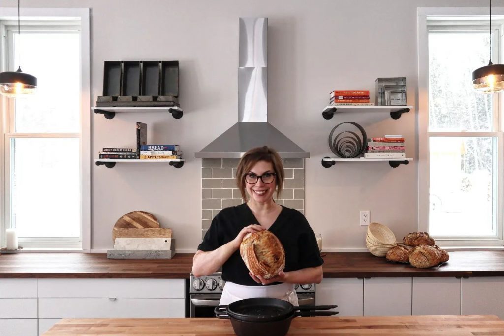 Lauren of Red Hen Artisinale holding a load of sourdough bread in a bright kitchen
