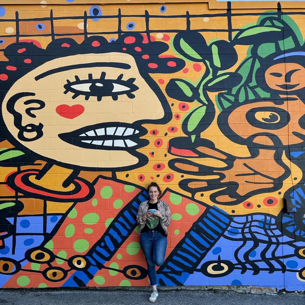 gabby holding a coffee in front of andrew lewis mural in st. thomas