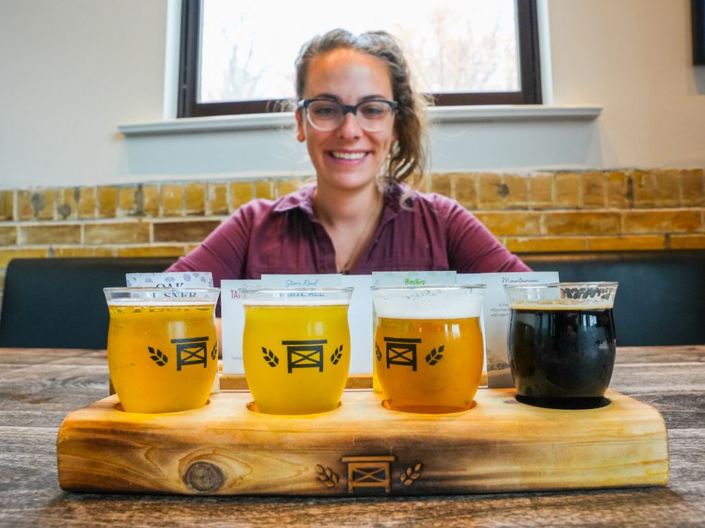 Gabby smiling at a flight of beers at Bench Brewing