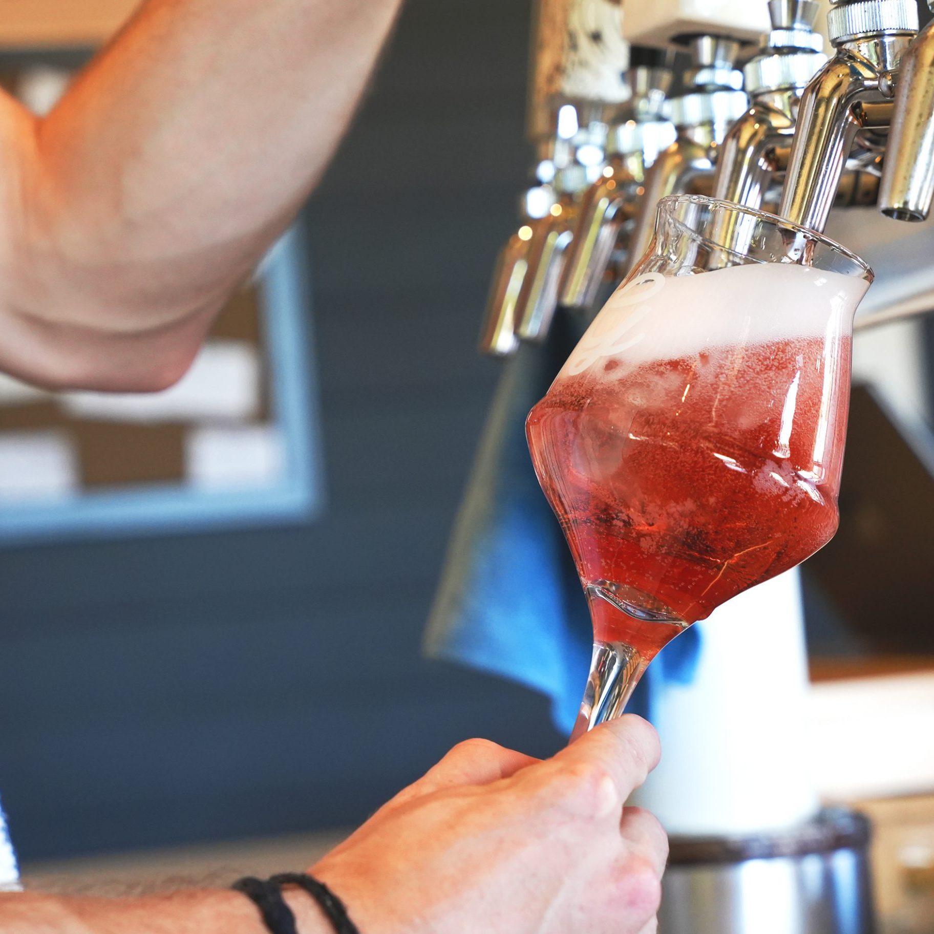 a hot pink sour beer being poured into a stemmed glass from OG bottle shop in galt