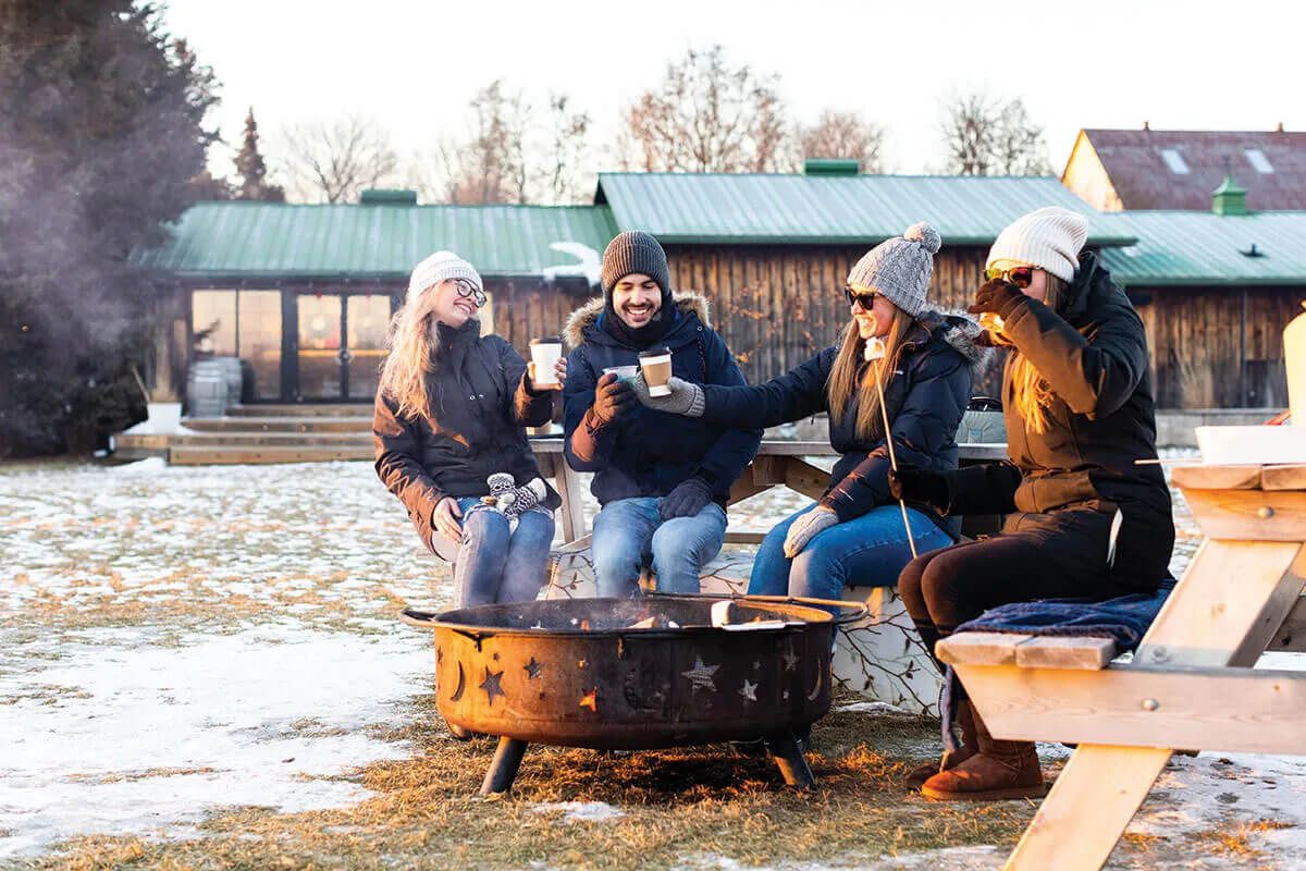 A group of people gather around an outdoor firepit at West Avenue Cider House