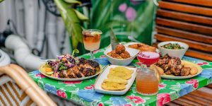 A picture of a outdoor patio table with a variety of Jamaican style plates.