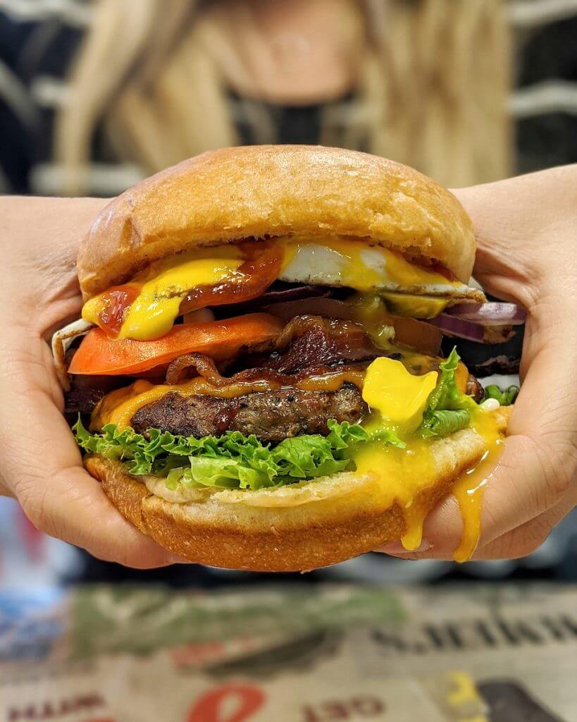 giant juicy burger being held by two hands