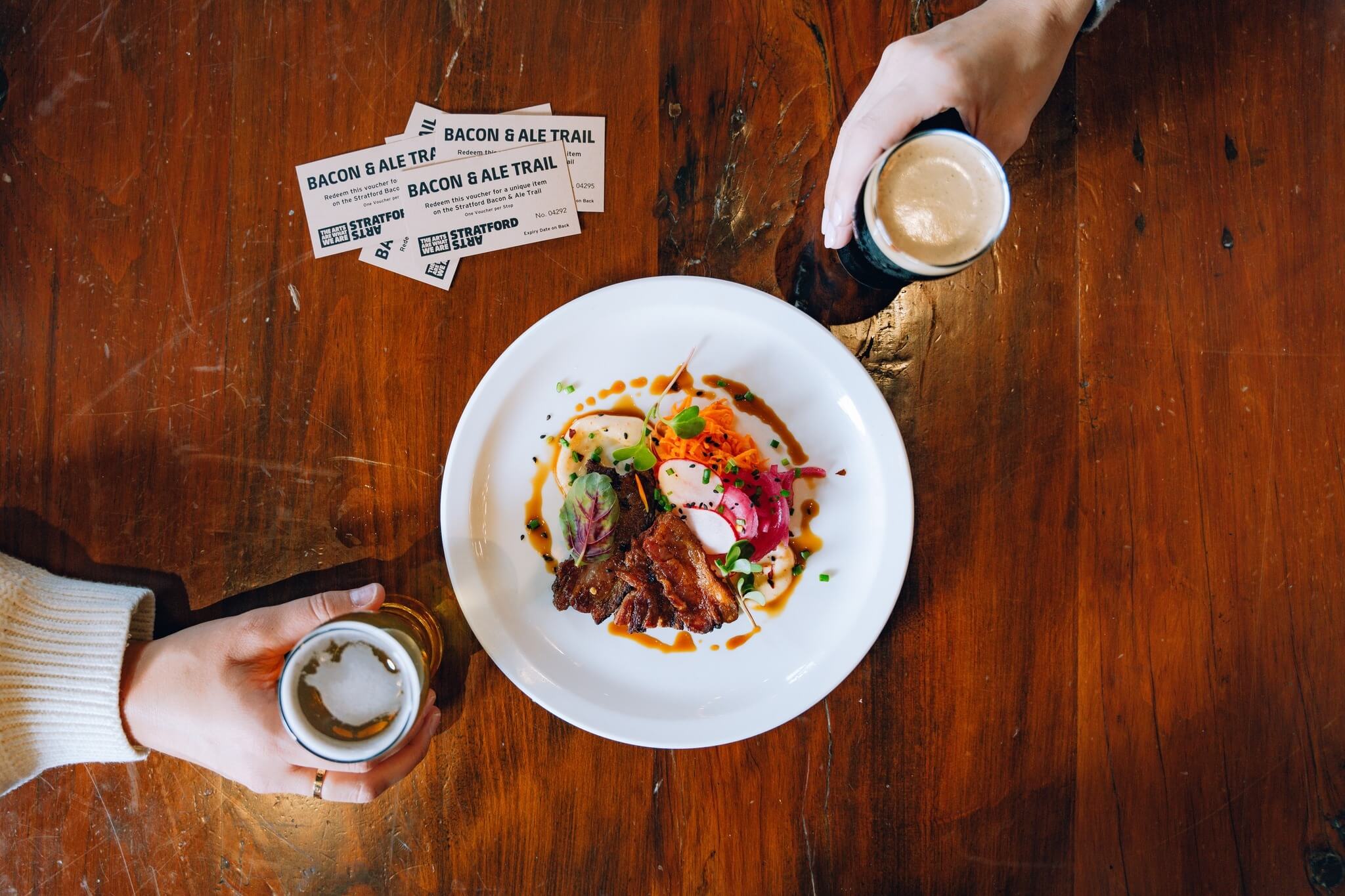 overhead shot of meal, two beers and passes for the bacon and ale trail