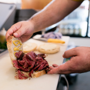 Two hands creating a roast beef sandwich