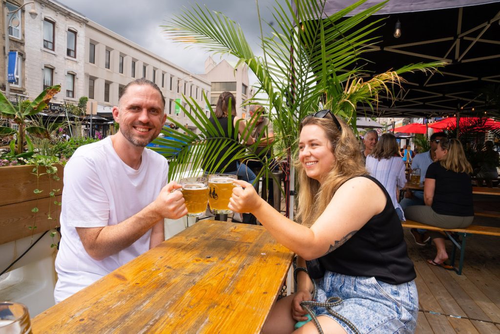 Ian and Chelsea cheersing the tandem helles lager and lamplighter ipa on the patio at Brothers Brewing Co.