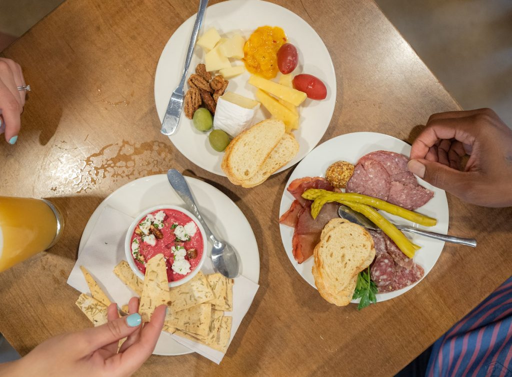 overhead shot of three snacks at wellington with Gabby and Royden's arms reaching in to grab stuff.