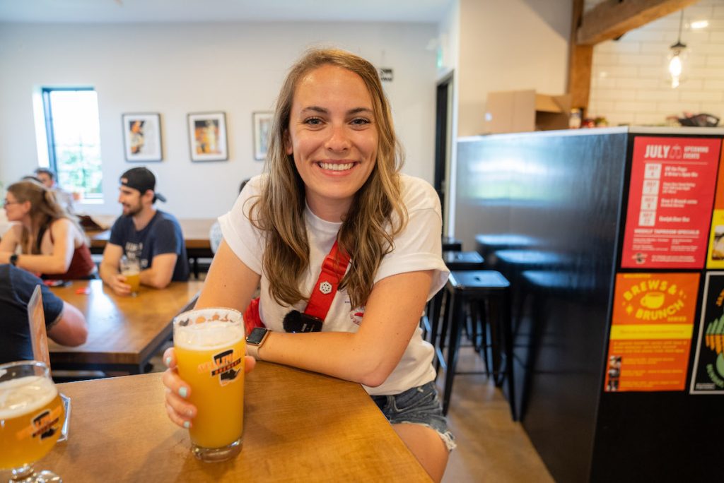 Gabby enjoying a Queen of Craft IPA at the high top tables inside Wellington Brewery