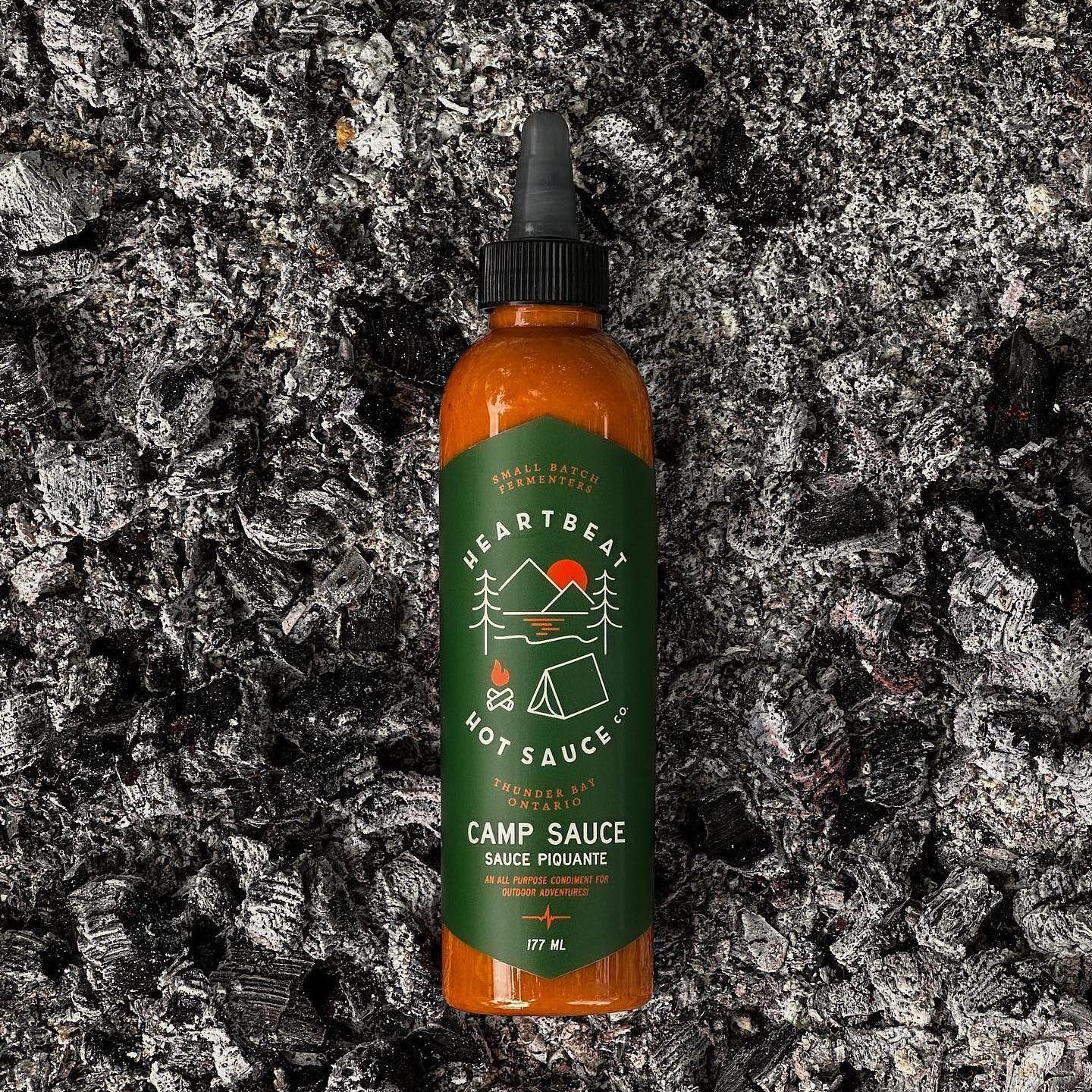 bottle of camp sauce lying on coals
