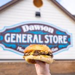 burger held up in front of Dawson General Store sign