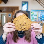 Person holding a giant cookie in front of their face at Kamview Nordic Centre