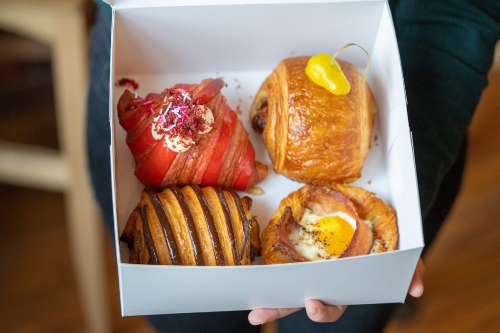 Box of four baked goods from Swell Bakery: Red Velbet Croissant, cheese and pepper pain, pain au chocolat and an egg and bacon danish