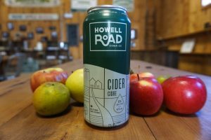 can of howell road cider in front of a pile of apples on a wood counter