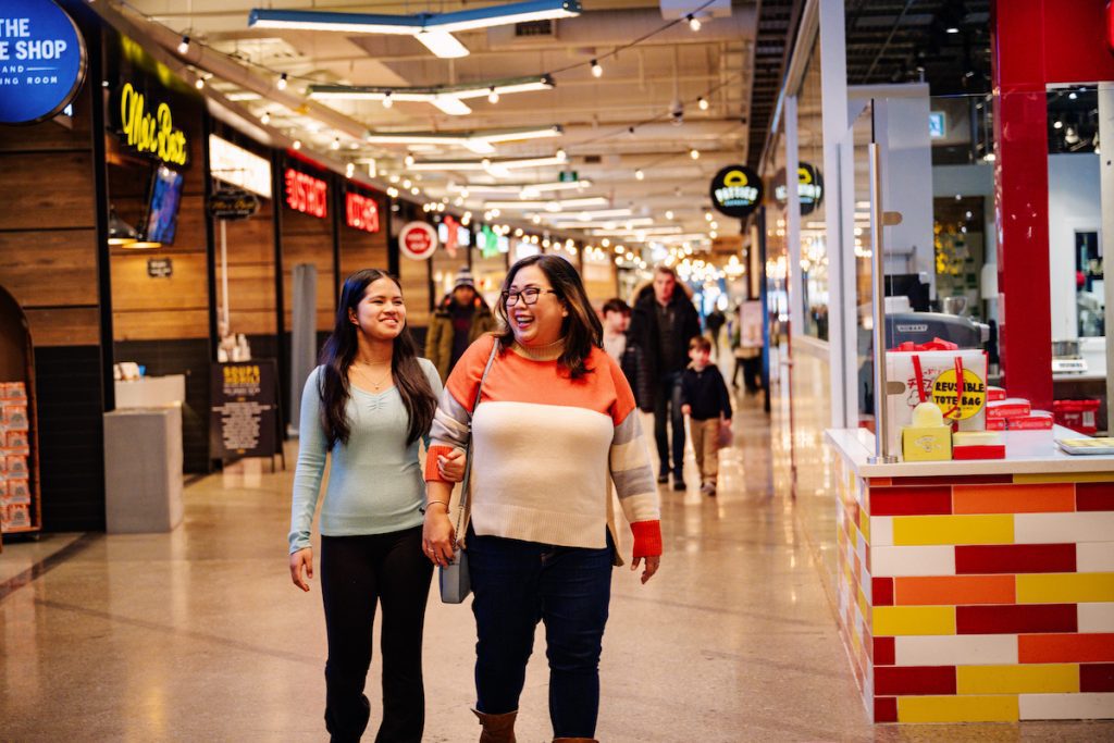 Two women walking together in the Food District in Mississauga Square One