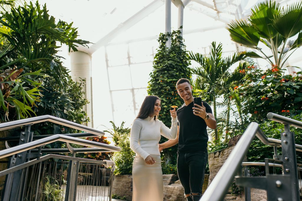 Couple in butterfly conservatory, woman with butterfly on finger