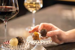 hand grabbing a truffle with two glasses of wine