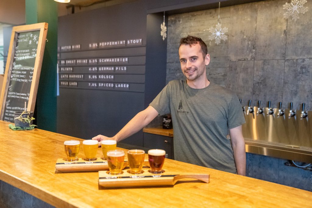 shot of the bartender at Dawson Trail with two flights of beer