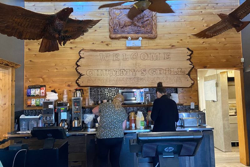 Photo of Chummy's Grill Cafe Counter with wood carving figurines hanging from ceiling.