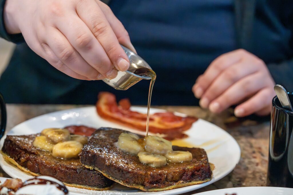 Close up photo of pouring maple syrup over french toast plate 