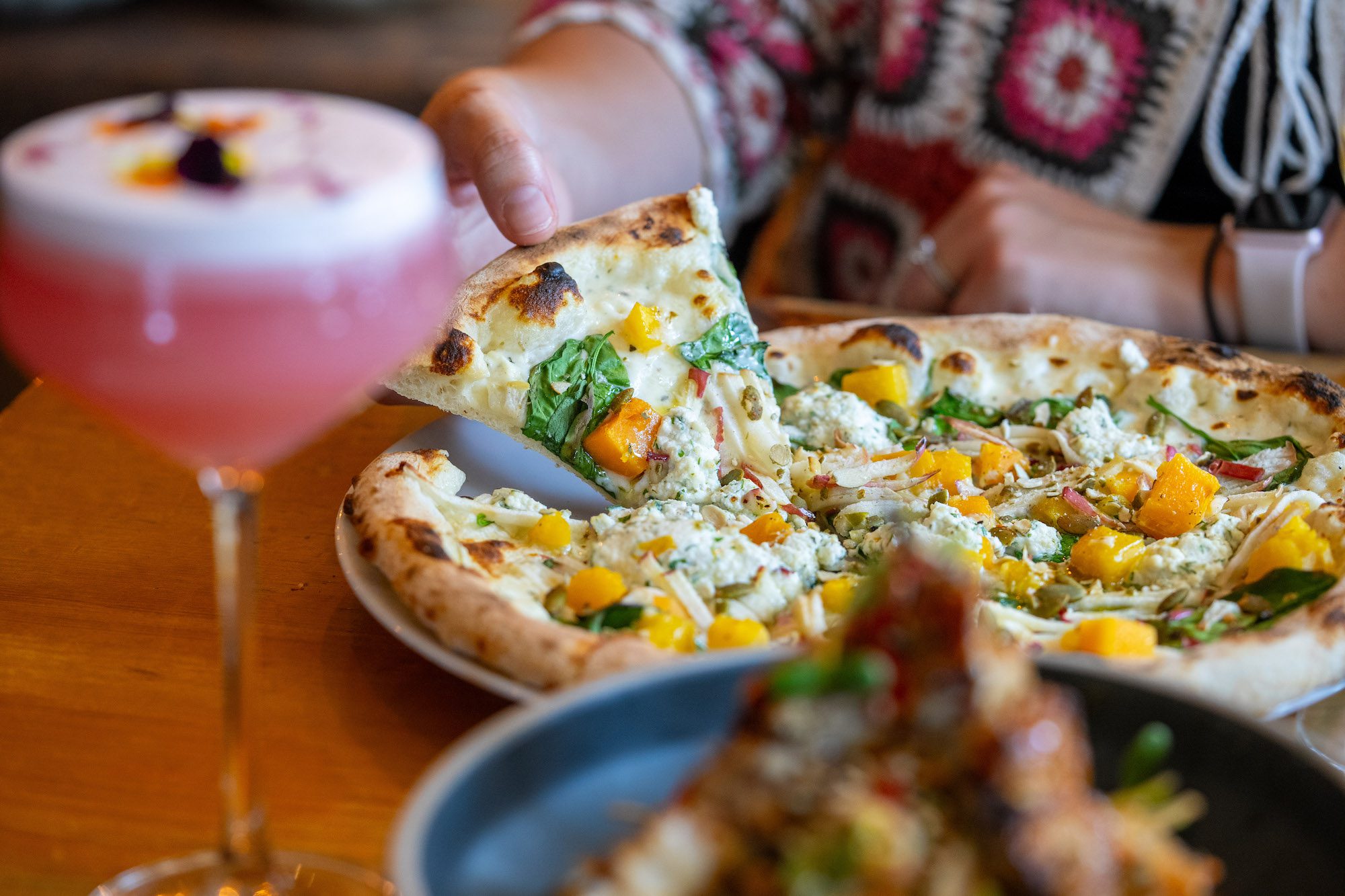 close up of a hand grabbing a slice of pizza at Bruce Wine Bar