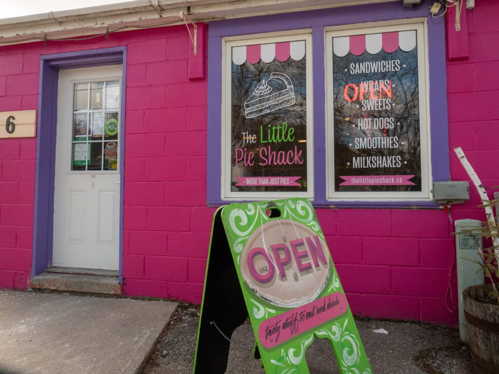 Pink exterior of the pie shack with a bright green open sign.