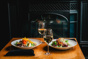 photo of two plates of food and two glasses of wine.