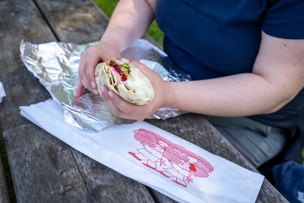 T holding a shawrma on a picnic table