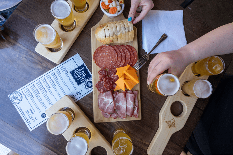 Overhead image of charcuterie board with three flights of beer glasses.