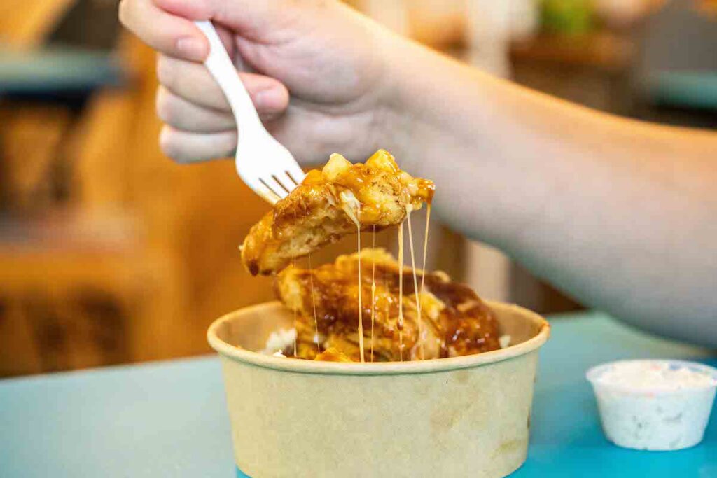 close up shot of a cheese pull from a halibut poutine