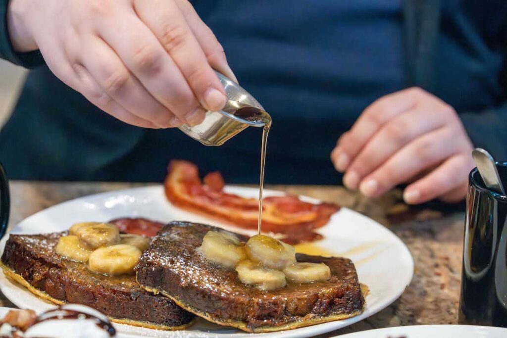 Tetiana pouring maple syrup over monkey bread at the Breakfast Pig