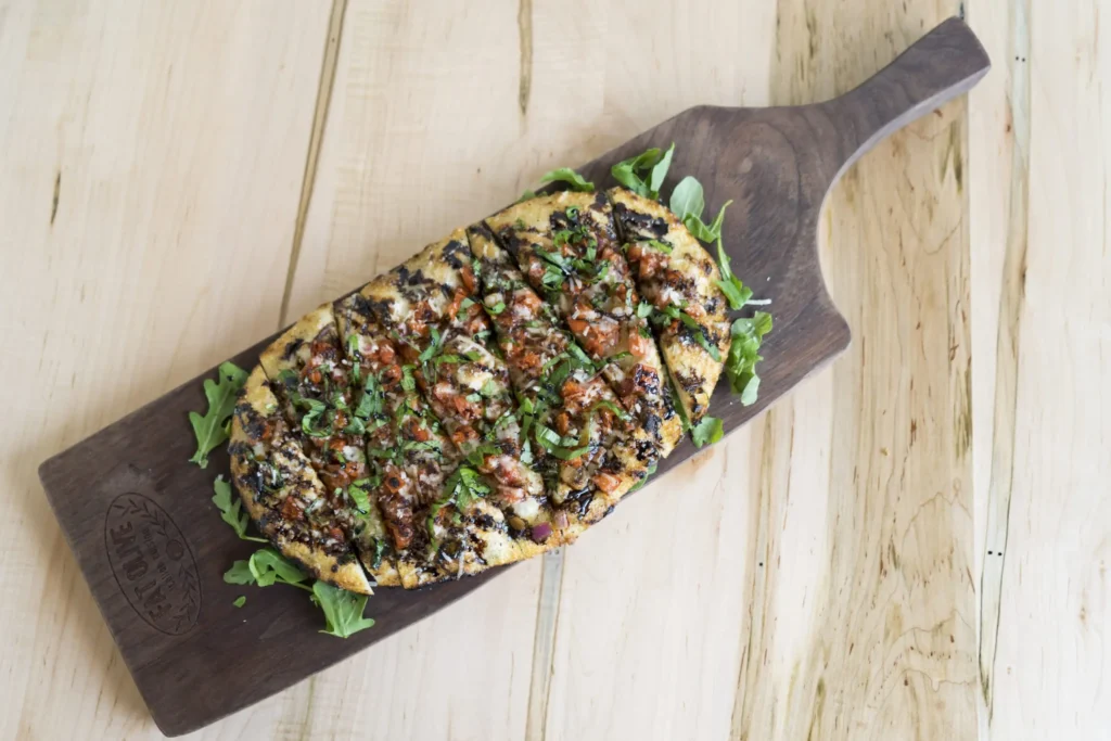 Fat Olive serving board with loaded flatbread dish.