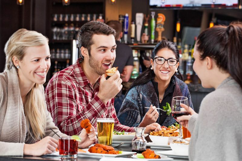 Image of friends eating a meal together at a table at The Pub at FireRock.