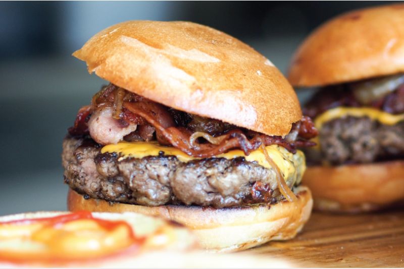 Close up image of burger topped with onions and melted cheese.