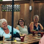 Group of 5 people enjoying beverages at a table on a patio at Crown and Turtle Pub