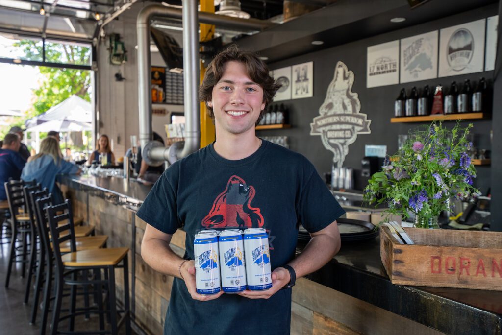 staff member holding a six pack of beer