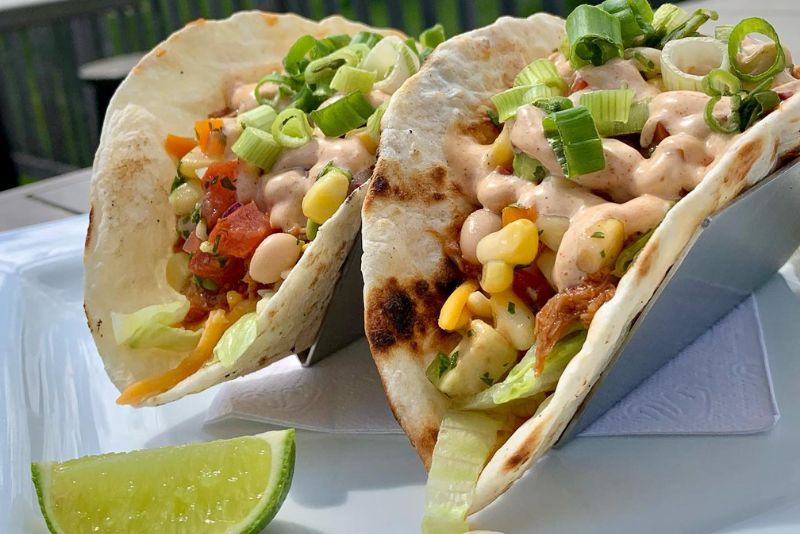 Close up image of two fish tacos served with lime wedge.