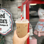 holding a drink up to the sign at Bearded Barista