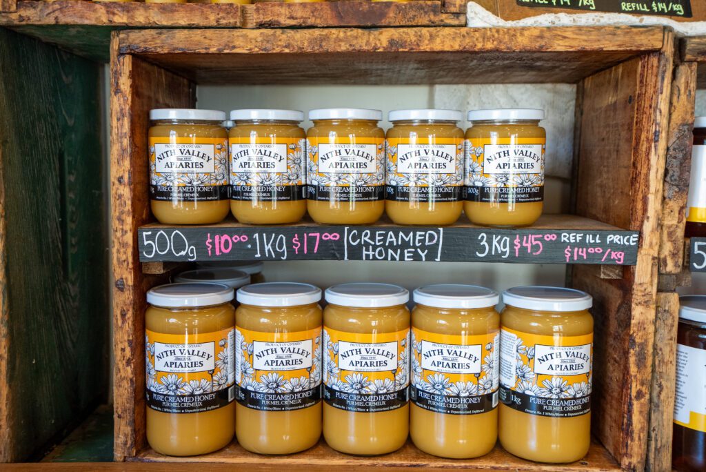 Close up shot of shelves stocked with Nith Valley Apiary Honey's.